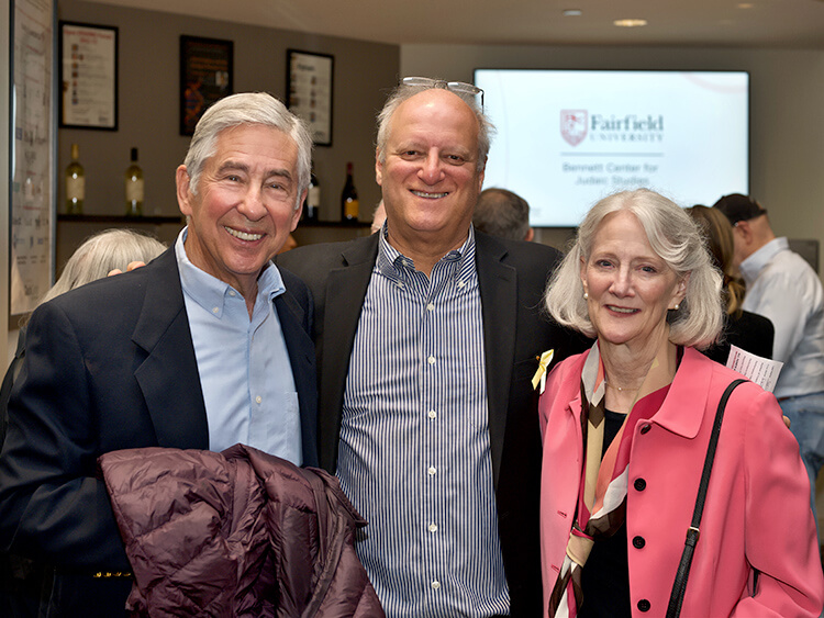 David Zieff and Evan and Barbara Salop at an event. Background shows a Fairfield University sign, creating a cheerful and formal atmosphere.